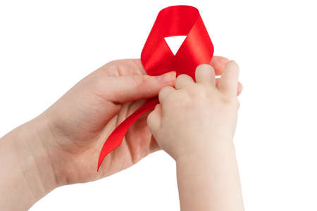 Aids red ribbon on woman's and child's hands support for World aids day.