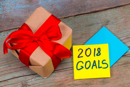 2018 goals - handwriting in black ink on a sticky note with a gift with red ribbon , New Year...