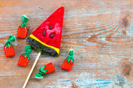 Colorful candies and lollipop watermelon on a wooden background. Top view with copy space.の写真素材