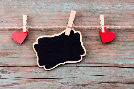 A red heart shape and a blackboard with Happy Valentine's Day text on rustic wooden table.の写真素材