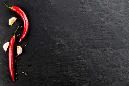 Red hot chili peppers and peppercorns on black background, top view with copy space.の写真素材