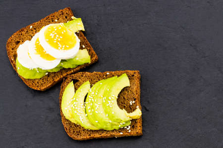 Sandwich with avocados and eggs,on a black stone background, top view.の写真素材