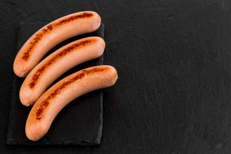 Grilled sausages on a dark stone with copy space.の写真素材