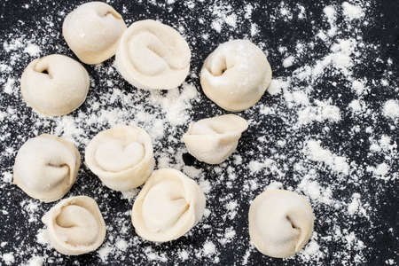 Traditional russian pelmeni, ravioli, dumplings with meat on black  stone background . Copyspace.の写真素材