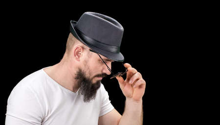 Silhouette of young confident handsome bearded man hipster in hat and sunglasses. Studio shot on...