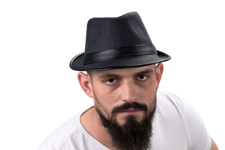 severe bearded man in hat looking at camera isolated on white background. With copy space.