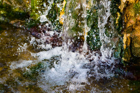 Quickly flowing mountain stream, close-up flowing water from the rock.