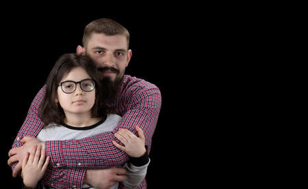 Portrait of handsome father and his cute daughter hugging, looking at camera and smiling.の写真素材