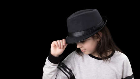 little girl in a hat with a brim on a black background.の写真素材