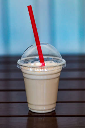 Vanilla milkshake covered with whipped cream in plastic glass on wooden background.の写真素材