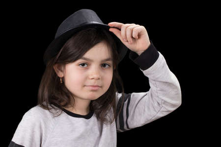 little girl in a hat with a brim on a black background.の写真素材