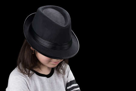  girl in cap with head tilted on black background.