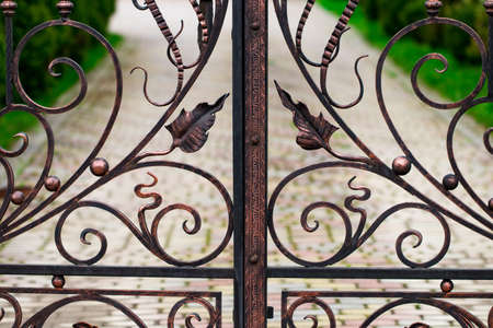 A closed forged metal gate looking onto a garden path.の写真素材