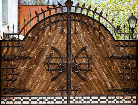 wooden gate with wrought iron elements close up.の写真素材
