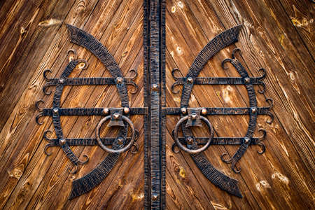 wooden gate with wrought iron elements close up.の写真素材