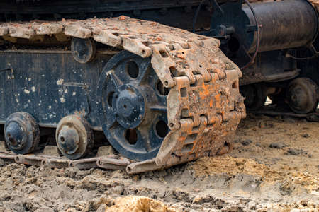 Tracked excavator work construction road .Close up of steel wheels crawler cranes, backhoes tracks.