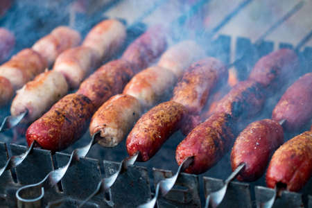 Close up of  grilling sausages on bbq on warm summer day.
