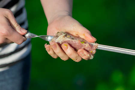 Female hands planted pieces of meat kebab skewer barbecue grill. Close up of skewers with juicy meat.の写真素材