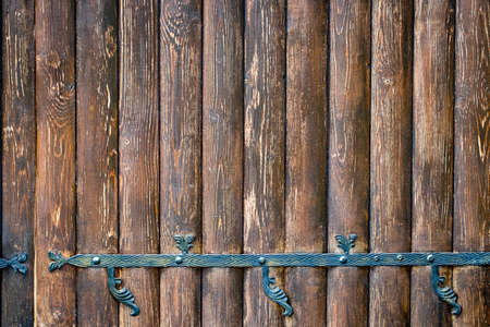 wooden gate with wrought iron elements close up.の写真素材