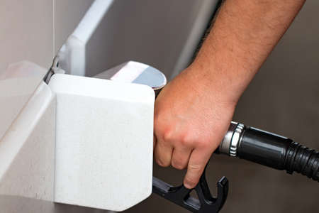 white car is refueled to a gas station, a refueling gun in the filler neck of a gasoline tank car.