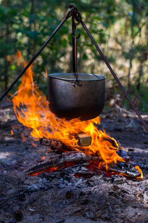 Tourist pot hanging over the fire on a tripod. Cooking in the campaign.の写真素材