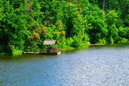 Relaxing gazebo built on the river against the forest.の写真素材