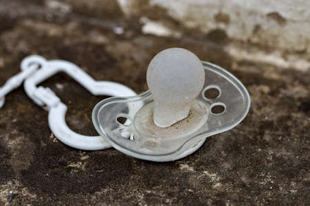 dirty silicone pacifier lying on the ground.