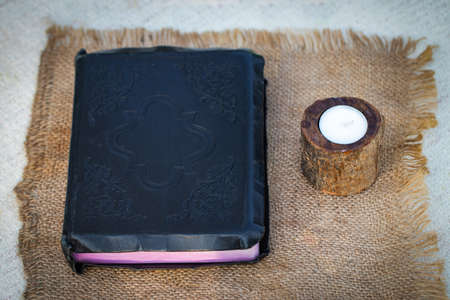 Bible and candle on a burlap napkin.