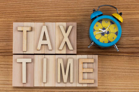 tax time -  text in vintage letters on wooden blocks with alarm clock.の写真素材