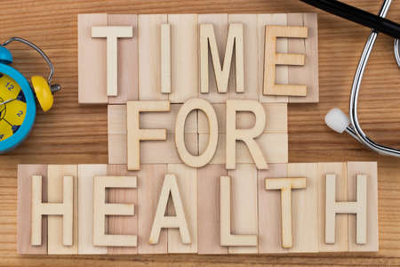 time for health -  text in vintage letters on wooden blocks with stethoscope and alarm clock. Medicine concept.の写真素材