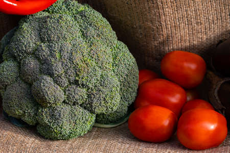 vegetables tomatoes and broccoli on burlap background.