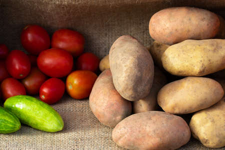 vegetable potatoes, tomatoes and cucumbers on the background of burlap.
