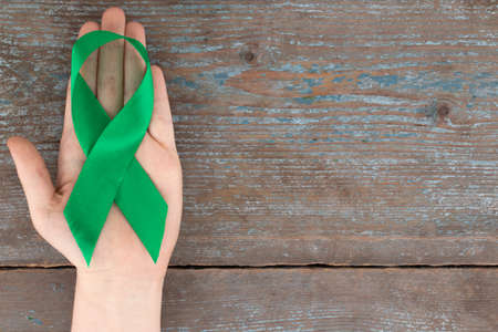 Green ribbon. Scoliosis, Mental health and other, awareness symbo on the wooden background with copy space.の写真素材