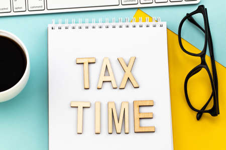 Tax Time - wooden letters with tax form, and cup of coffee.の写真素材