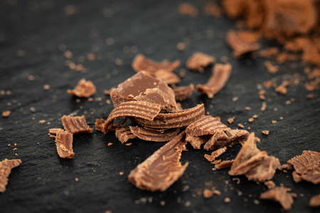 Broken chocolate pieces and cocoa powder on a dark background.