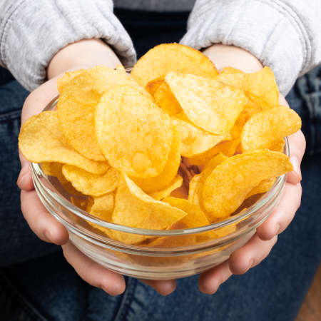 Female hand giving crispy potato chips bowl.