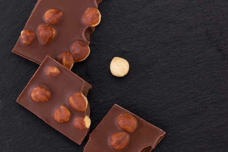 milk or dark chocolate with nuts on black background.