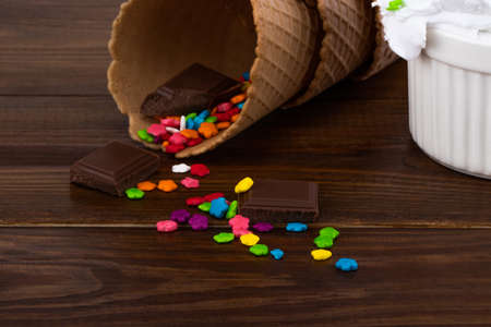Plate of vanilla ice cream scoop with sprinkles and waffle cones on wooden  with copy space.