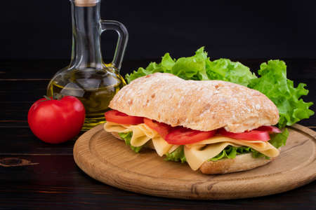 Ciabatta sandwich with lettuce , prosciutto and  cheese on wooden board.の写真素材