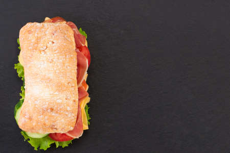 Ciabatta sandwich with lettuce , prosciutto and  cheese over stoneの写真素材