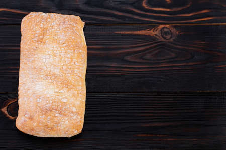 ciabatta bread on a cutting board on the dark wooden table, top view with space.の写真素材