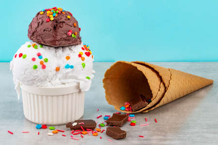 plate of vanilla and chocolate ice cream scoops swith sprinkles chocolate pieces and waffle cones on...