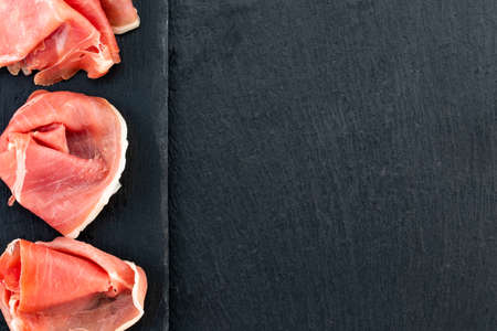 Italian prosciutto crudo or spanish jamon and sausages. Raw ham on stone cutting board, copy space, top view.の写真素材