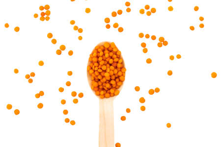 red lentils on wooden spoon isolated on white background.