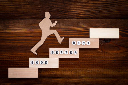 Good - Better - Best, paper man climbing the steps to success in a conceptual image over woodenの写真素材