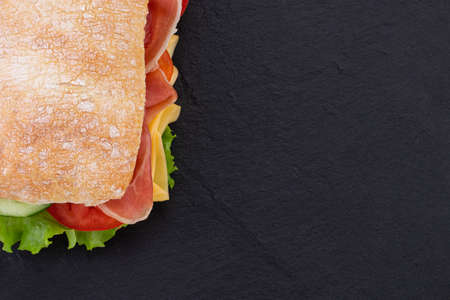 Ciabatta sandwich with lettuce, prosciutto and  cheese over stoneの写真素材