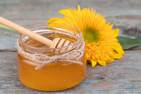 Honey background. Fresh honey in the pot with sunflower flower.の写真素材