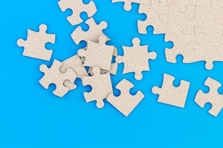 Unfinished white jigsaw puzzle pieces on blue