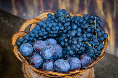 plums and grapes in a wooden bowl.
