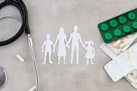 Paper silhouette of family with stethoscope, pills, tablets and capsules. Family healthcare,...